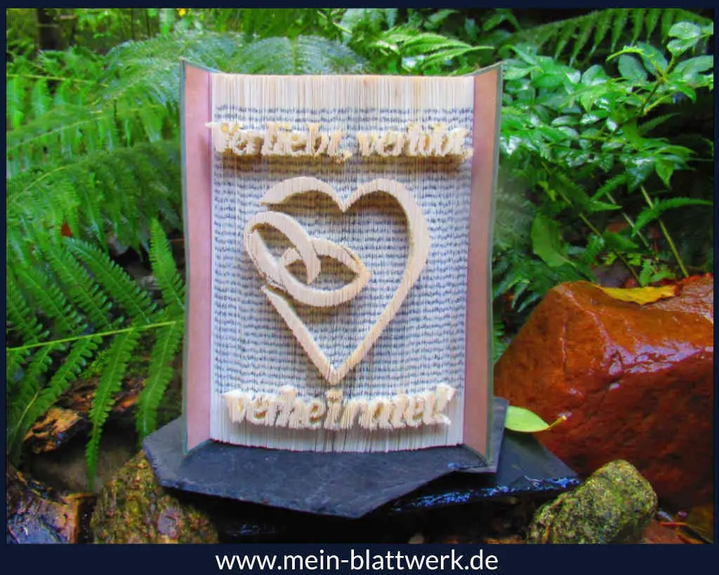 Kostenlose Buchfalten-Vorlage zum Ausdrucken für ein Hochzeitsbuch. Ein Herz mit Eheringen in einem Buch als Hochzeitsgeschenk.