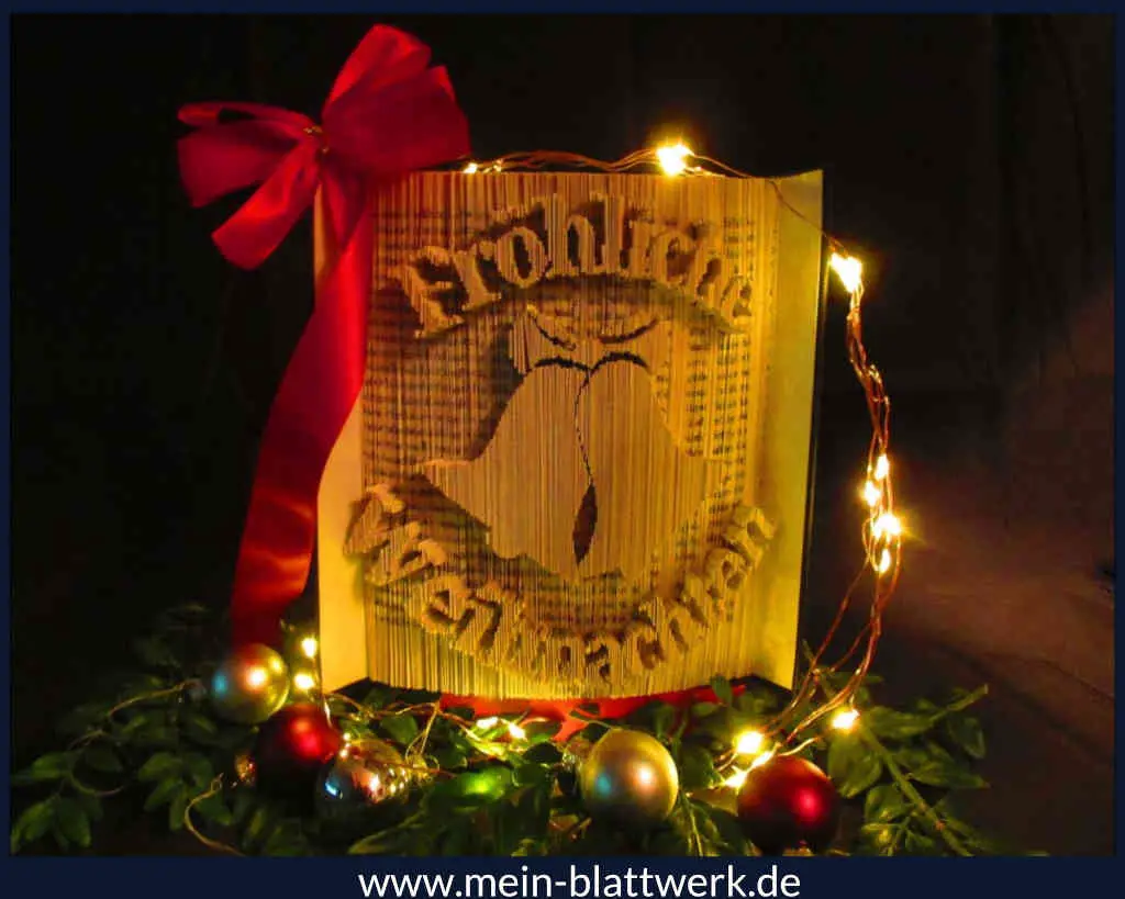 Buchkunst: "Fröhliche Weihnachten" und Weihnachtsglocken in einem Buch. Weihnachtsdekoration selber machen.